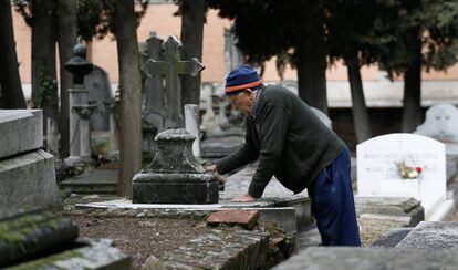 Urbano, de 78 años, limpia una lápida en el cementerio civil de La Almudena, en Madrid.