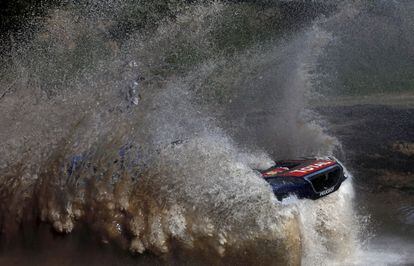 El pilóto de Peugeot Sebastien Loeb atraviesa de una zona de agua.