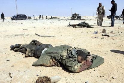 Rebeldes libios observan los cadáveres de supuestos soldados de las fuerzas de Gadafi, cerca de la carretera que une las localidades de Ajdabiya y Brega, en el este de Libia.