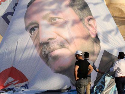 Trabajadores ajustan un poster de Erdogan en Mardin, en el sur de Turquía 