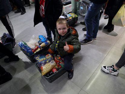Un niño sentado sobre una cesta de la compra en el primer supermercado reabierto en la ciudad de Jersón tras la liberación por el ejército ucranio.