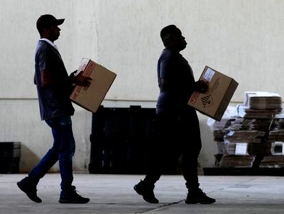 Dos empleados de las autoridades electorales llevan sendas urnas electrónicas a un centro de votación este jueves en Brasilia.