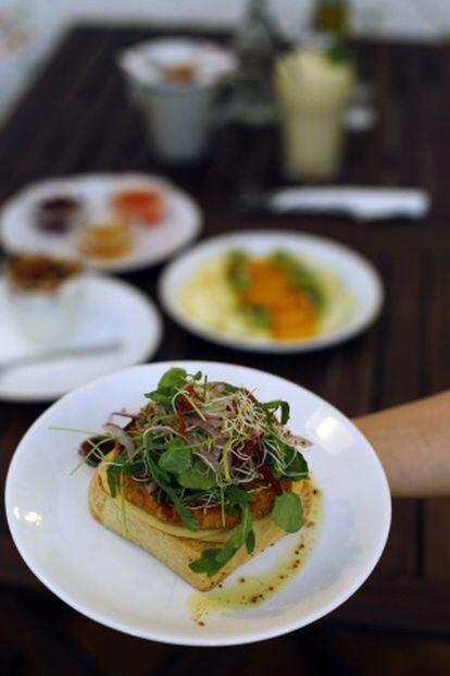 Hamburguesa vegetariana ante una mesa con platos naturales de Motha.