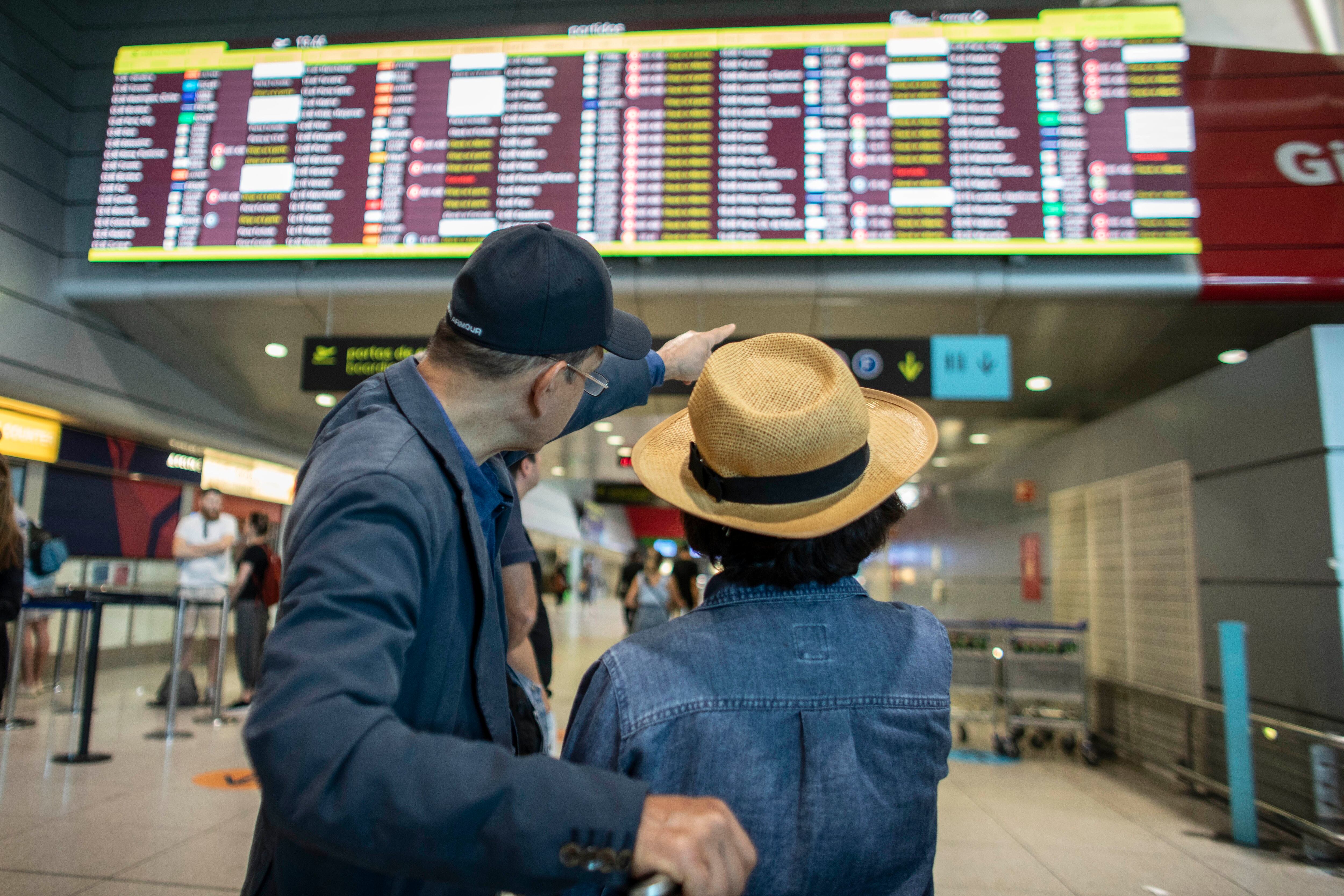 Dos turistas observaban el panel de información de vuelos en el aeropuerto de Lisboa, el pasado 3 julio.