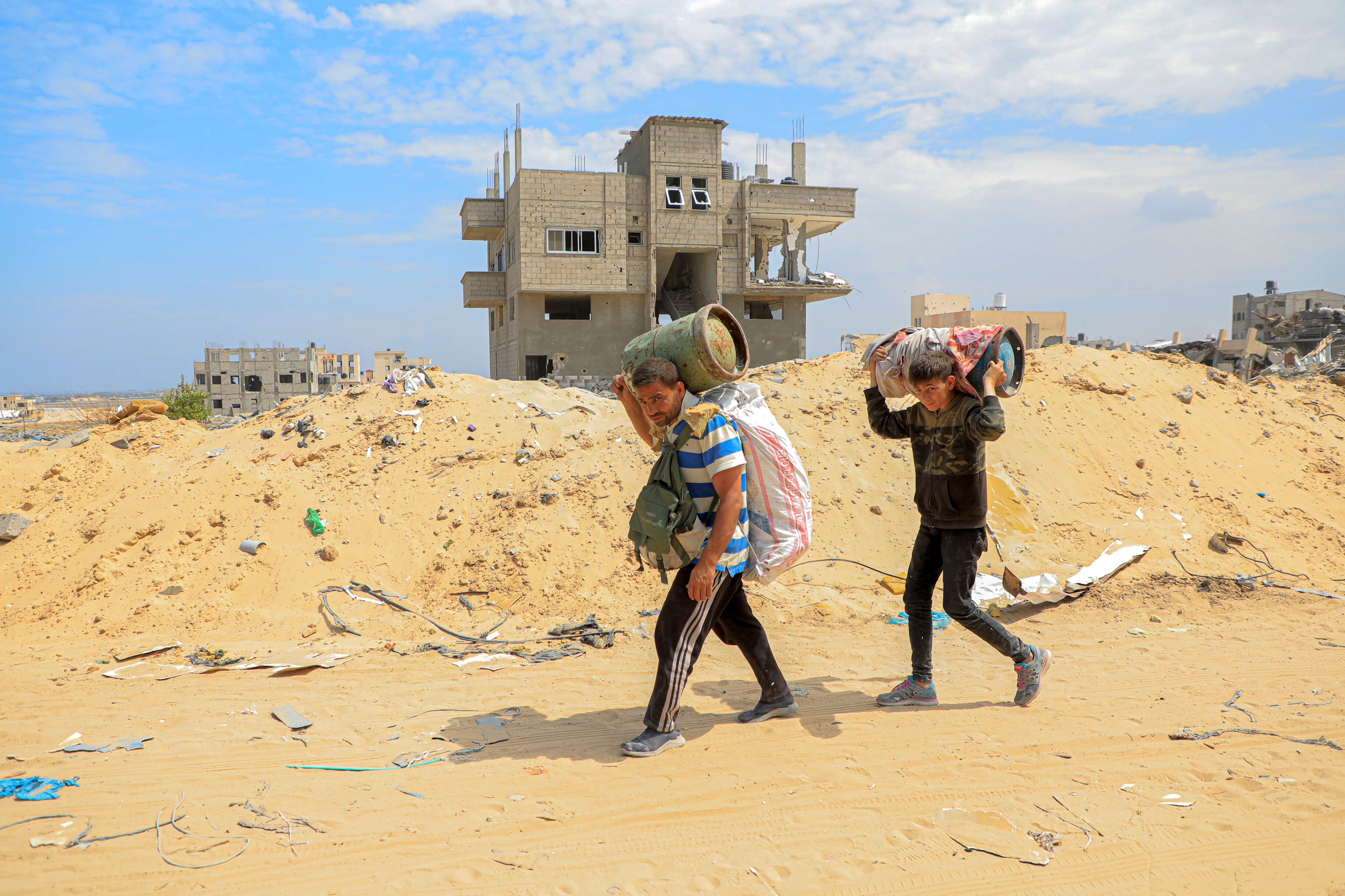 Palestinos vuelven con sus pocas pertenencias a la ciudad de Jan Yunis, en el sur de Gaza.