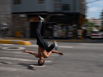 B-boy Kenyer Méndez, de 27 años, desliza su cabeza, usando un casco modificado frente a un semáforo, en Caracas.