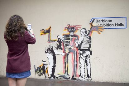 Una foven toma una foto de uno de los dos murales de Banksy.