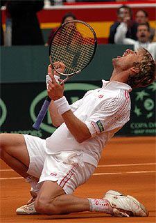 Juan Carlos Ferrero, rodilla en tierra, ojos cerrados, canta su último golpe triunfal.