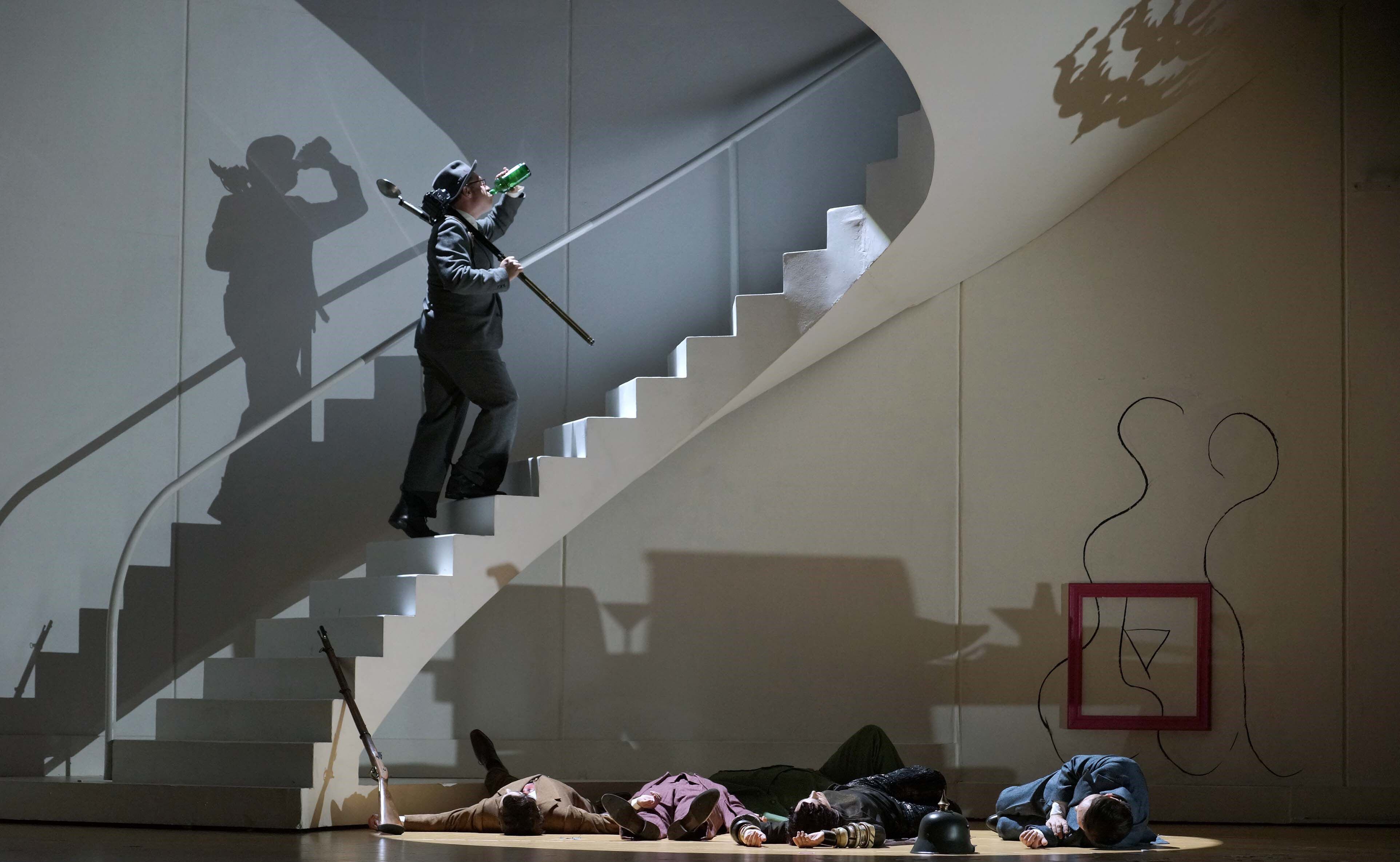 Emilio/Man Ray (Jeremy Ovenden) sube las escaleras tras fotografiar a Armindo, Rosmira, Parténope y Arsace) y cantar su aria 'Anch'io pugnar saprò' del primer acto.