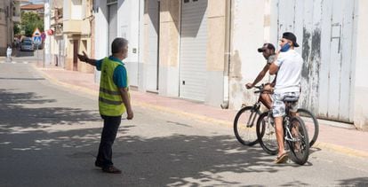 Agente cívico informa a unos jóvenes de la obligación del uso de la mascarillla en Alcarràs (Lleida).