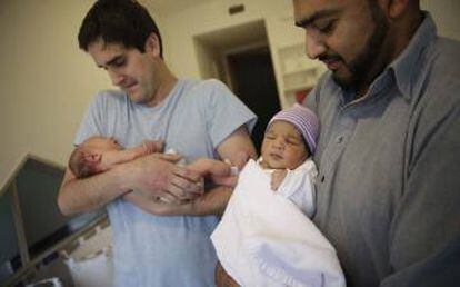 Dos padres con sus bebés en brazos.