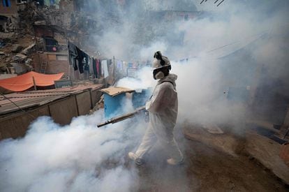Un integrante de una brigada de salud fumiga una calle para evitar la propagación del dengue en el distrito de San Juan de Lurigancho, en Lima