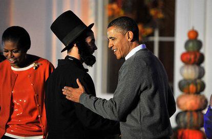 Barack y Michelle Obama reciben a un vecino disfrazado de Abraham Lincoln la noche de Halloween.