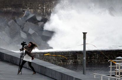 Una mujer lucha con el viento junto a la playa de La Zurriola de San Sebastián, donde se registran fuertes rachas de viento.