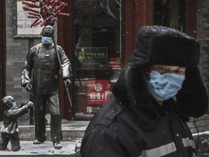 En foto, un hombre con mascarilla en una calle de Pekín con los establecimientos cerrados, el miércoles. En vídeo, China confirma la muerte por coronavirus del doctor Li Wenliang.