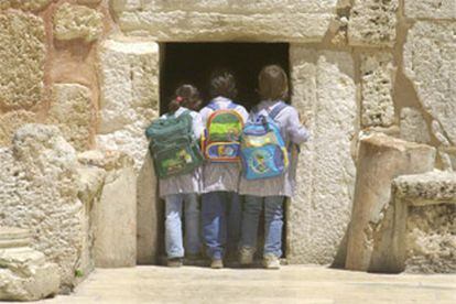 Tres niñas palestinas echan un vistazo a la basílica de la Natividad desde la Puerta de la Humillación.