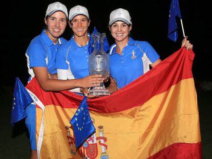 Carlota Ciganda (i), Azahara Muñoz (c) y Beatriz Recari posan con la Solheim Cup tras la bandera de España.
