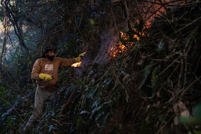 A member of the community tries to stop the spread of the fire with a machete.