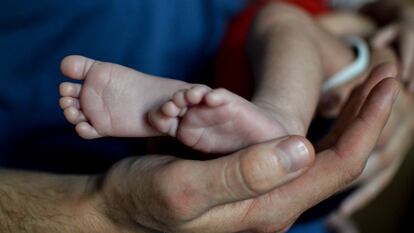 Un hombre sostiene a un niño nacido por gestación subrogada en México.