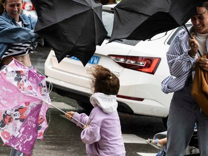Varias personas tratan de dominar sus paraguas en San Sebastián.