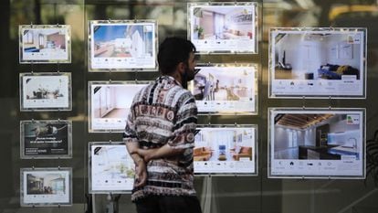 Un joven mira anuncios de alquiler de una inmobiliaria en Barcelona.