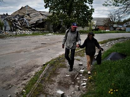 Una pareja camina delante de una vivienda bombardeada en Kupiansk.