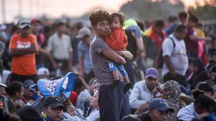 Un migrante centroamericano carga a su bebé en la última caravana de enero.