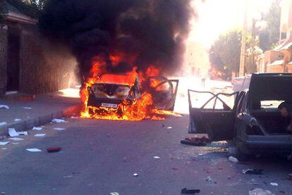 Un coche arde mientras otro es desmantelado en una calle de El Aaiún.