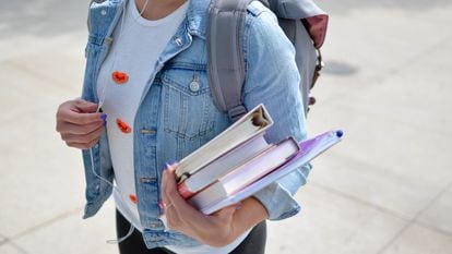 Una alumna universitaria carga material educativo de camino a su centro.