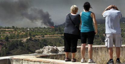 Los propietarios de una casa en la zona donde se ven las llamas se lamentan desde el castillo de Macastre (Valencia), el sábado.