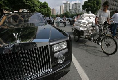 Un ciclista que acarrea sacos pasa junto a un Rolls-Royce en Shangh&aacute;i.