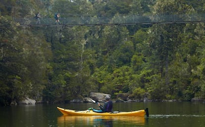 Senderistas y un kayakista cruzando la laguna de Sandfly Bay, en el parque nacional de Abel Tasman, en Nueva Zelanda.