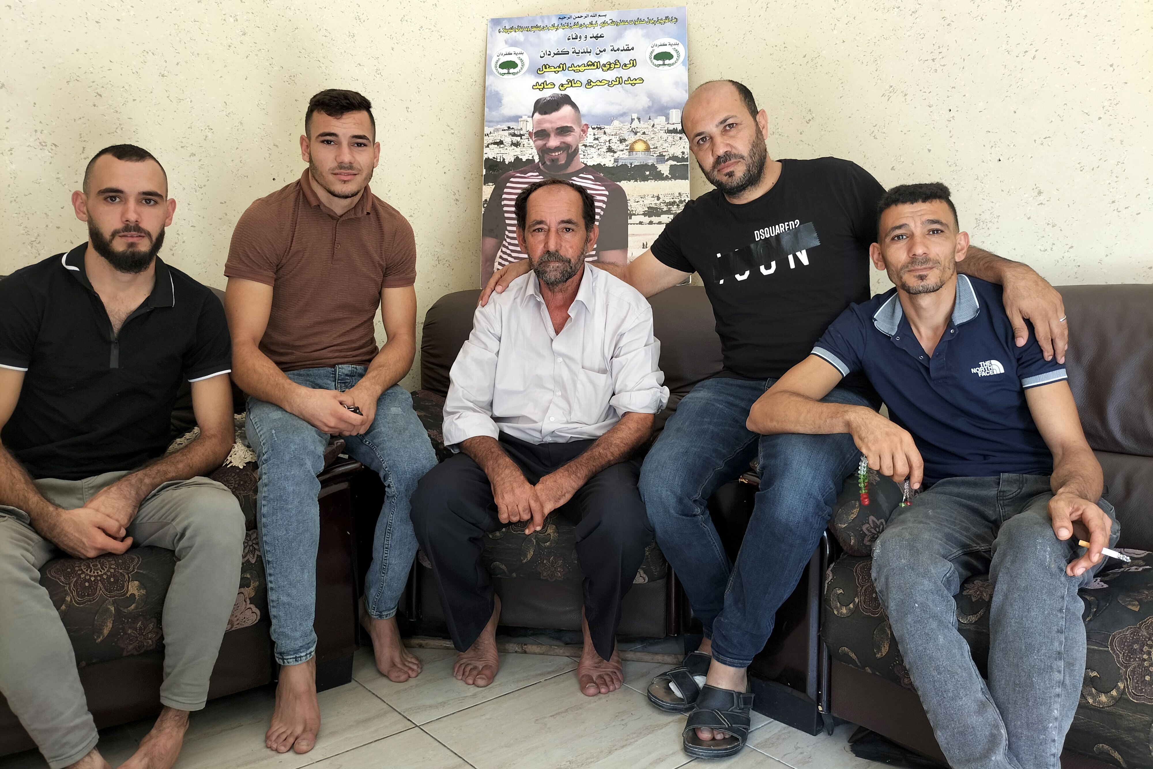 En el centro, Hani Abed, padre de Abdulrahman Hani Abed (cuya imagen aparece en el cartel), en su casa junto a otros miembros de la familia en Kafr Dan.