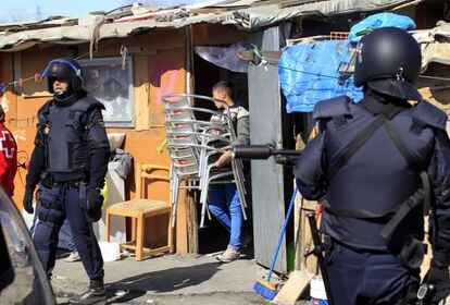 Voluntarios de la parroquia de Santo Domingo de la Calzada y de San Carlos Borromeo se han atrincherado en el poblado con los afectados para intentar evitar la actuación. En la foto, los agentes ordenan el desalojo de una de las viviendas. El dueño saca los muebles de su casa minutos antes de ser derrumbada.