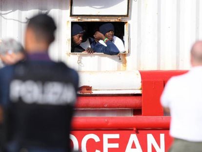 Dos migrantes miran por la ventana del barco de rescate 'Ocean Viking' al llegar al puerto italiano de Messina, el martes.