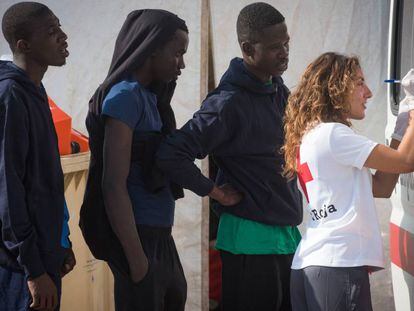 Una voluntaria de Cruz Roja atiende a varios inmigrantes ayer en Algeciras. 