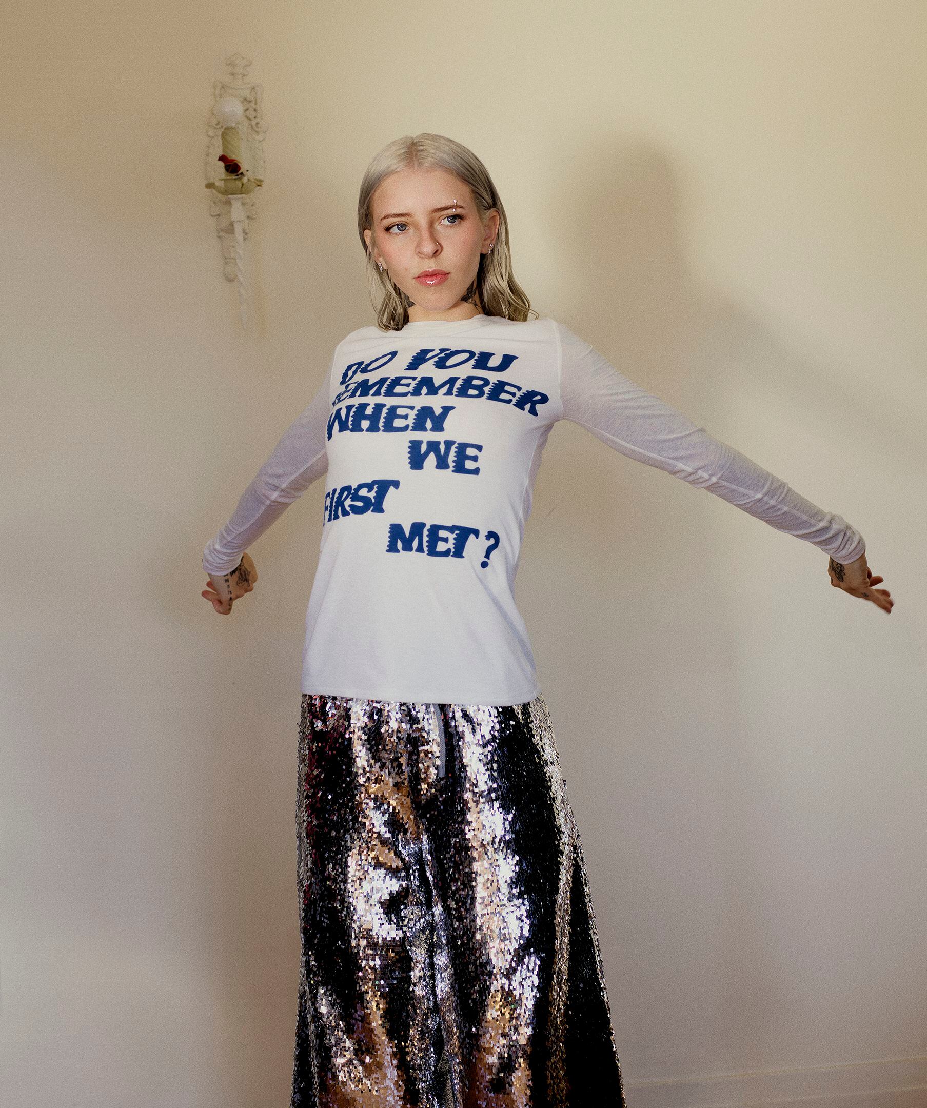La artista lleva camiseta con letras tejidas y falda de lentejuelas de LOEWE Paula’s Ibiza.