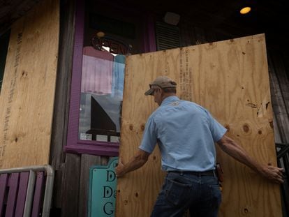Un hombre coloca tablas de madera para proteger un establecimiento antes de la llegada del huracán a Cedar Key (Florida), este martes.