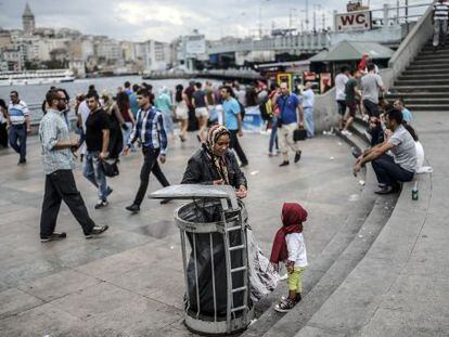 Un ni&ntilde;o sirio refugiado mira a su madre recoger basura en Estambul.