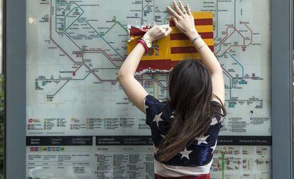 Una mujer vestida con una bandera de EE.UU arranca una bandera española en Barcelona.