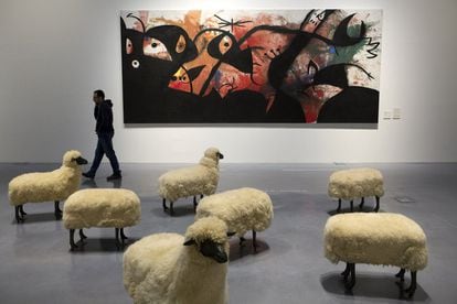 Una persona camina frente a las obras 'Troupeau de mouton' de Francois-Xavier Lalanne (en primer término) y 'Personajes y pájaros en la noche' de Joan Miró, que forman parte de la nueva exposición permanente del Centro Pompidou de Málaga, titulada 'Utopías modernas'.