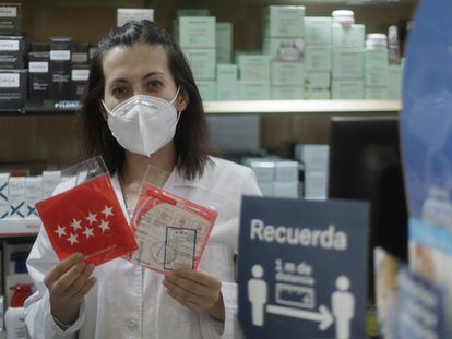 Una farmacéutica muestra una mascarilla del Gobierno regional en una farmacia de la capital.