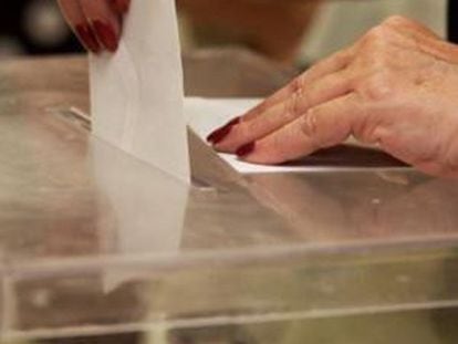 Una persona introduce su voto en una urna.