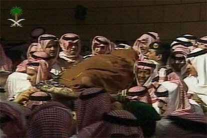 Imagen de la televisión saudí del traslado del cuerpo del rey Fahd, sobre una tabla y envuelto en un sudario blanco.