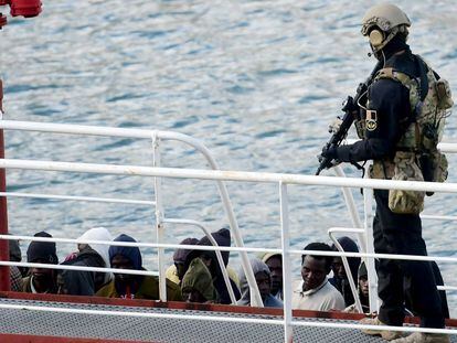 Un policía armado vigila a un grupo de inmigrantes a bordo del barco petrolero El Hiblu 1, en el Gran Puerto de La Valeta (Malta).