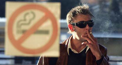 Un hombre fuma en la puerta de un bar de Madrid ante un cartel de prohibici&oacute;n