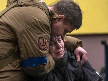 A soldier comforts Larysa Kolesnyk, 82, after she was evacuated from Irpin, on the outskirts of Kyiv, Ukraine, Wednesday, March 30, 2022. (AP Photo/Rodrigo Abd)