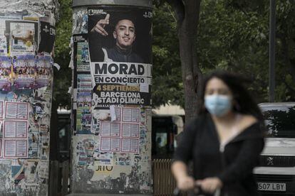 Una dona passa davant d'un cartell anunciant un concert de Morad a l'Hospitalet de Llobregat.