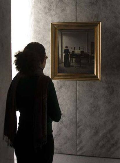 Una visitante contempla la obra <i>Interior. Salón con piano y mujer vestida de negro</i> (1901), de Hammershoi.