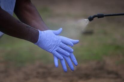 Un miembro de un equipo de enterramiento se lava las manos después de recoger el cuerpo de un fallecido por ébola cerca de Monrovia, Liberia.
